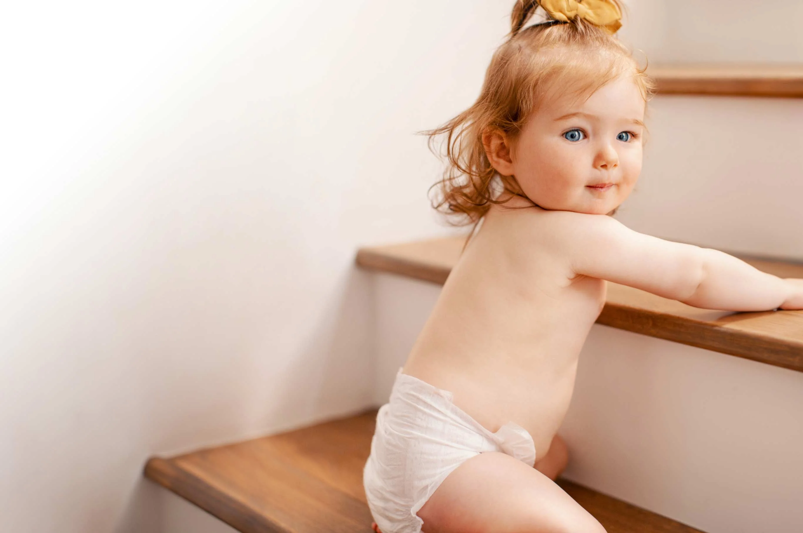A baby crawling up wooden stairs